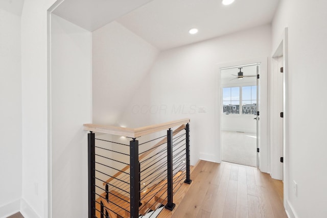 hallway featuring light wood-style flooring, baseboards, recessed lighting, and an upstairs landing