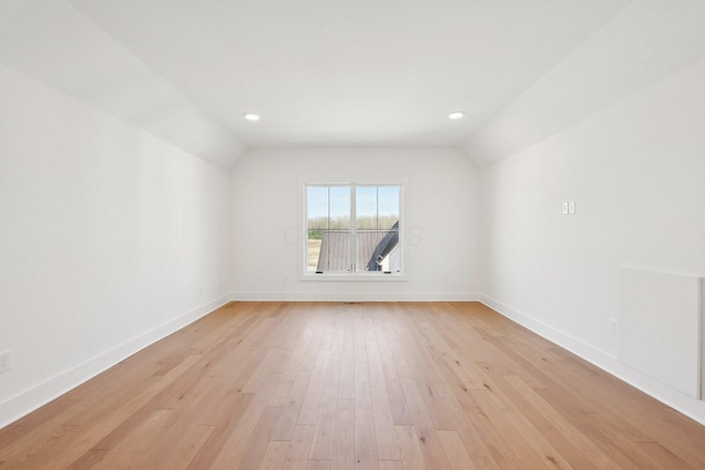 empty room featuring recessed lighting, vaulted ceiling, light wood finished floors, and baseboards