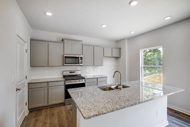 kitchen featuring sink, dark hardwood / wood-style floors, decorative backsplash, light stone countertops, and stainless steel appliances