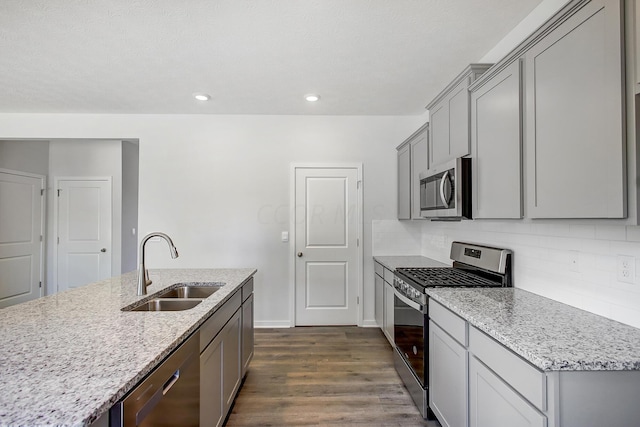 kitchen featuring light stone countertops, sink, dark hardwood / wood-style flooring, backsplash, and appliances with stainless steel finishes