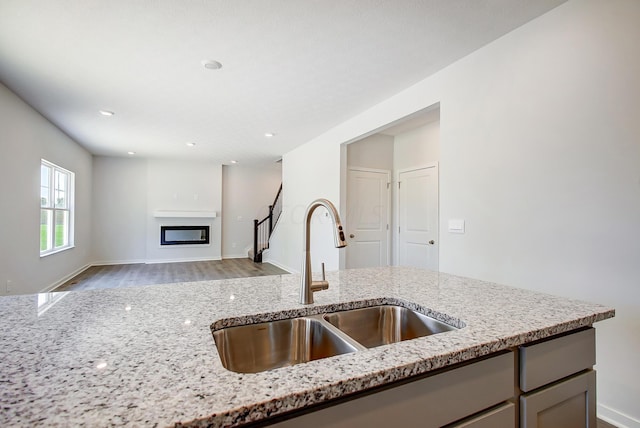 kitchen featuring light stone counters, sink, and light wood-type flooring