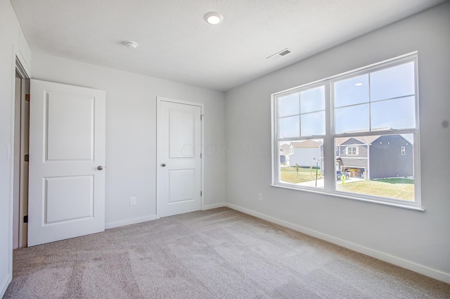 unfurnished bedroom featuring a textured ceiling and light carpet