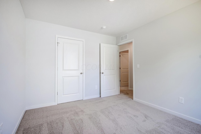 unfurnished bedroom with light carpet and a closet