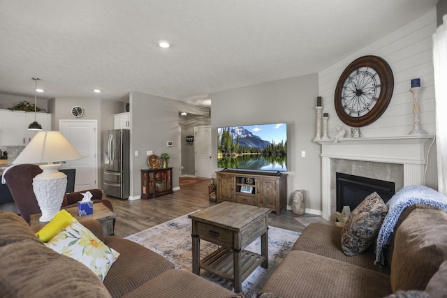 living room with a textured ceiling, dark wood-type flooring, and a tiled fireplace