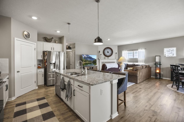 kitchen featuring white cabinetry, sink, stainless steel refrigerator with ice dispenser, and an island with sink