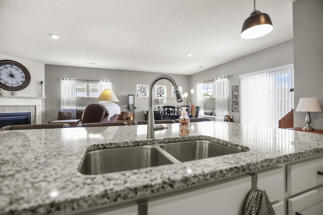 kitchen with light stone countertops, plenty of natural light, pendant lighting, and sink