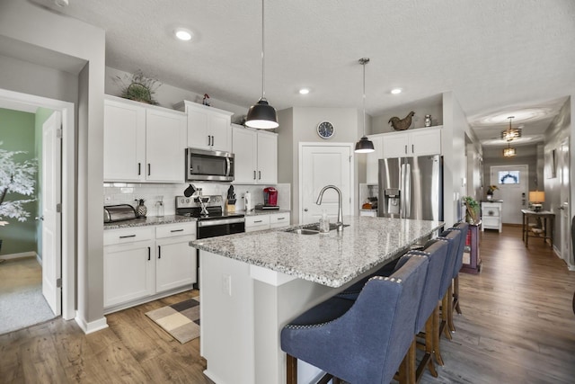 kitchen featuring a center island with sink, white cabinets, sink, and stainless steel appliances