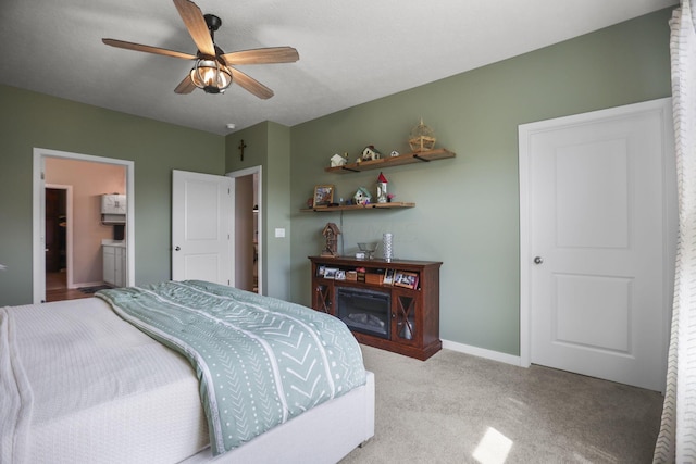 bedroom with ceiling fan, light colored carpet, and ensuite bath