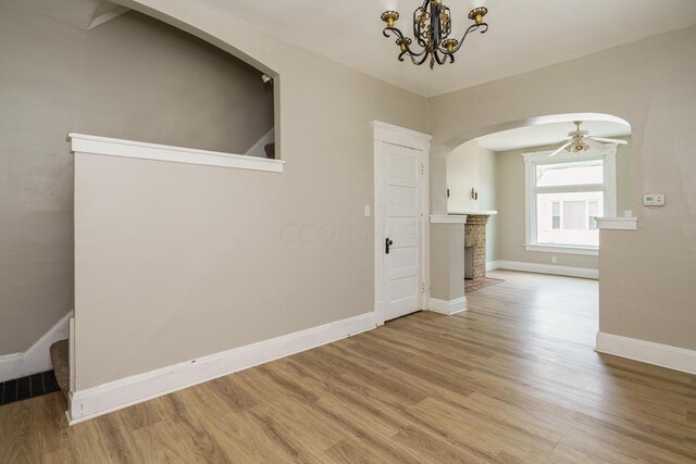 interior space with ceiling fan with notable chandelier and light wood-type flooring