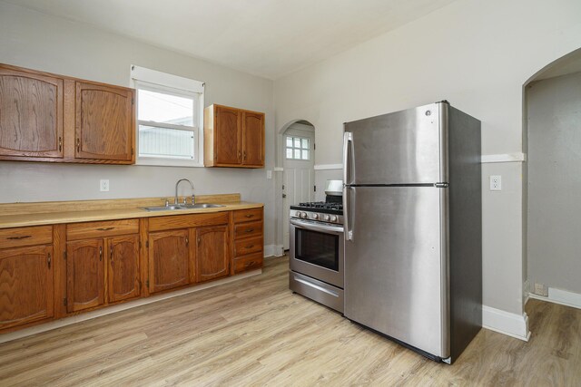 kitchen with stainless steel appliances, a wealth of natural light, and light hardwood / wood-style floors