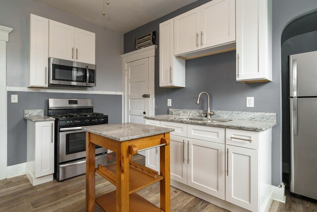 kitchen with dark hardwood / wood-style flooring, sink, white cabinets, and stainless steel appliances