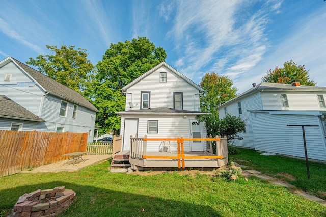 rear view of property featuring a deck, an outdoor fire pit, and a lawn