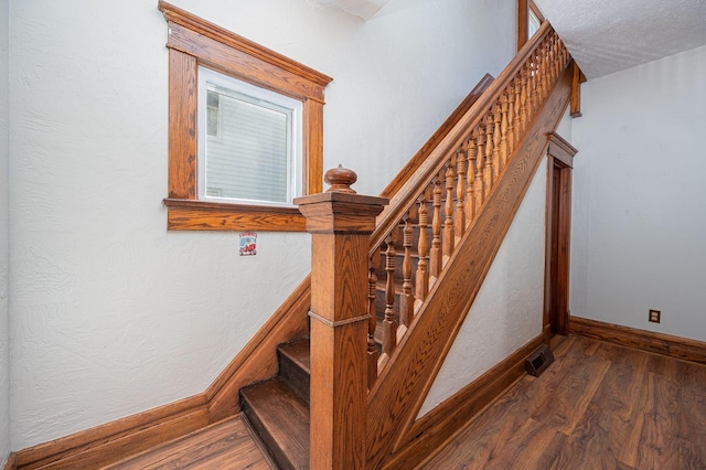 stairs featuring hardwood / wood-style flooring and a textured ceiling