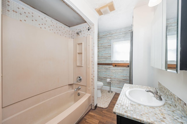 full bathroom with a textured ceiling, toilet, shower / washtub combination, vanity, and hardwood / wood-style flooring