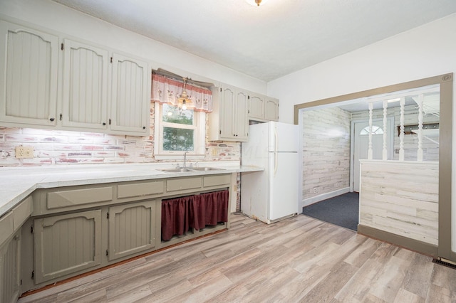 kitchen featuring backsplash, sink, white fridge, and light hardwood / wood-style flooring