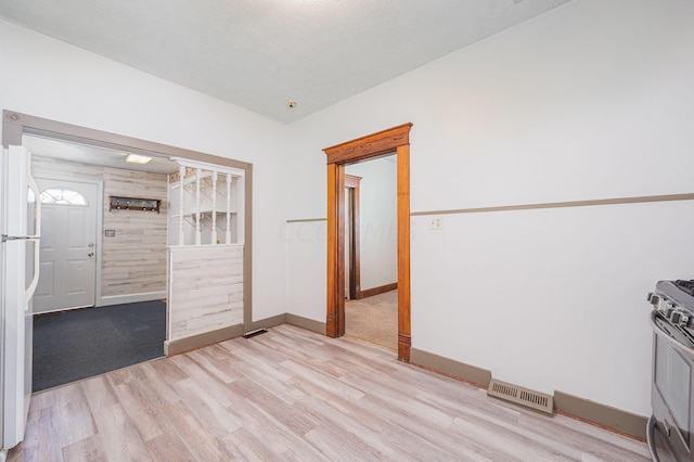 interior space with wood walls, light hardwood / wood-style flooring, and a textured ceiling