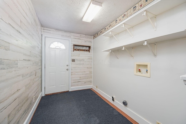 laundry area featuring dark colored carpet, hookup for a washing machine, a textured ceiling, and wooden walls