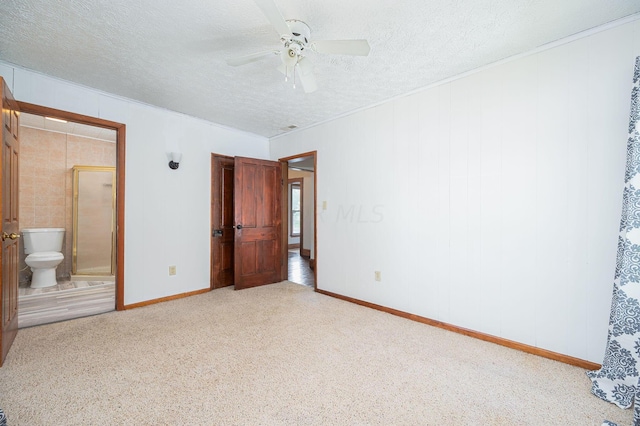 unfurnished bedroom featuring a textured ceiling, ensuite bathroom, and ceiling fan