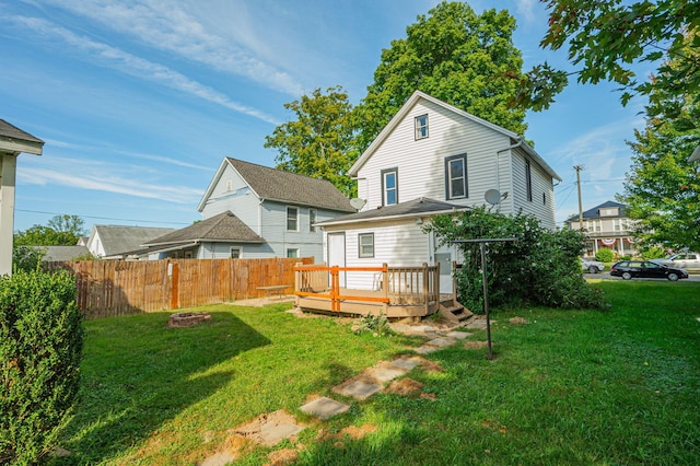 rear view of house featuring a wooden deck, a yard, and an outdoor fire pit