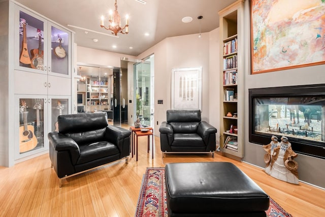 living area featuring a multi sided fireplace, a chandelier, built in features, and wood-type flooring