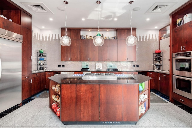 kitchen featuring a center island, stainless steel appliances, tasteful backsplash, dark stone countertops, and pendant lighting