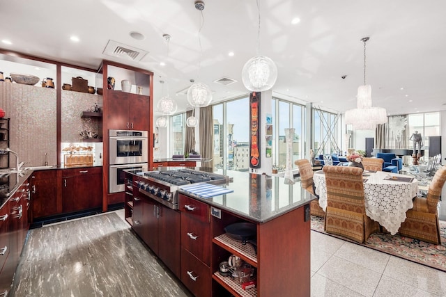 kitchen featuring appliances with stainless steel finishes, decorative light fixtures, a kitchen island, and a healthy amount of sunlight