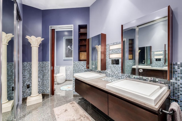 bathroom with vanity, toilet, tile walls, and decorative columns