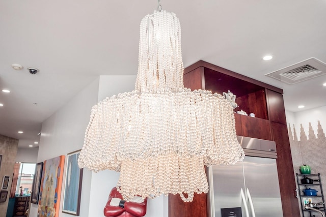 interior details featuring stainless steel refrigerator with ice dispenser and an inviting chandelier