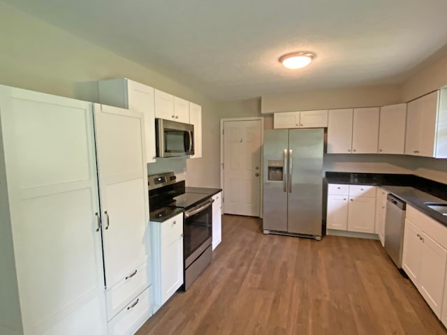 kitchen featuring hardwood / wood-style flooring, white cabinets, and appliances with stainless steel finishes