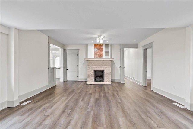 unfurnished living room featuring a fireplace, light wood-type flooring, and ceiling fan