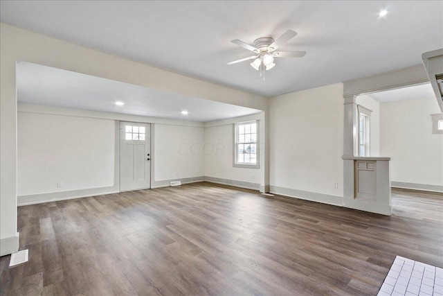 unfurnished living room featuring plenty of natural light, ceiling fan, and dark hardwood / wood-style flooring