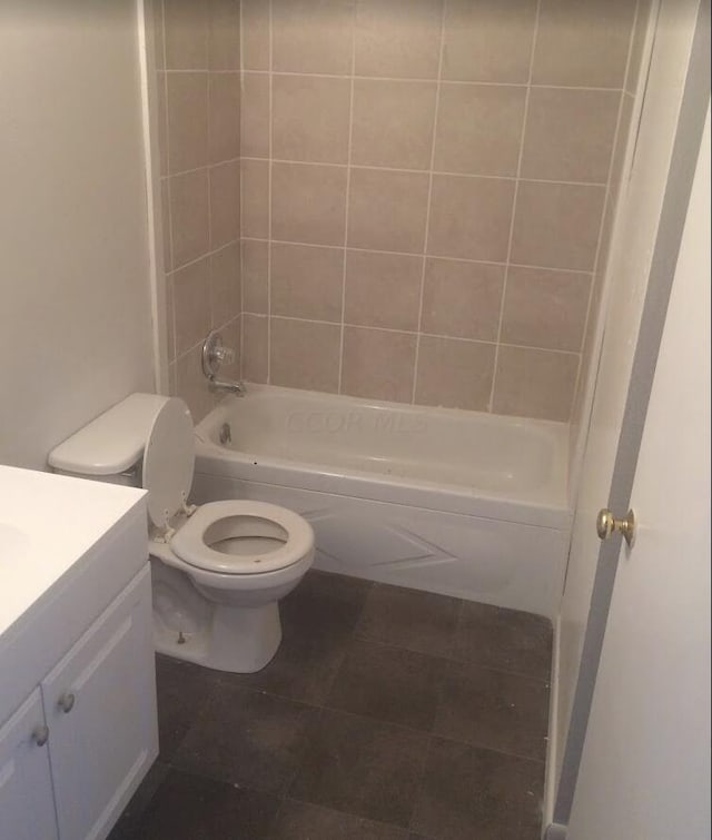 full bathroom with tile patterned floors, vanity, tiled shower / bath combo, and toilet