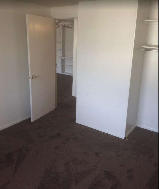 unfurnished bedroom featuring dark colored carpet and a closet