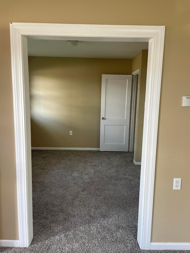 hallway with dark colored carpet