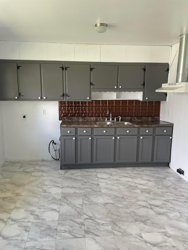 kitchen with gray cabinetry, sink, exhaust hood, and tasteful backsplash