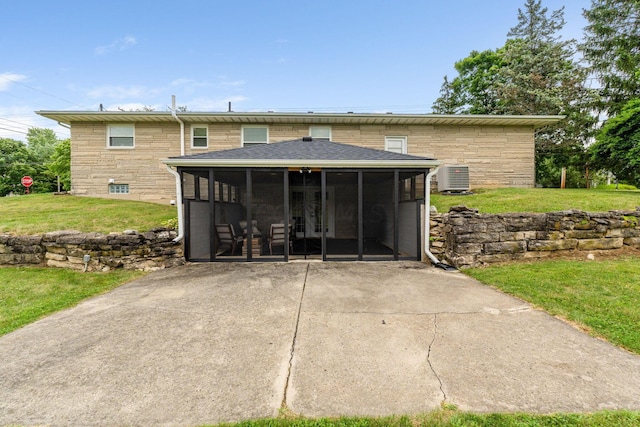 rear view of house featuring a lawn, a sunroom, and central AC unit