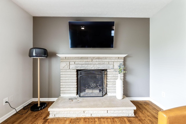 room details featuring wood-type flooring, a textured ceiling, and a stone fireplace