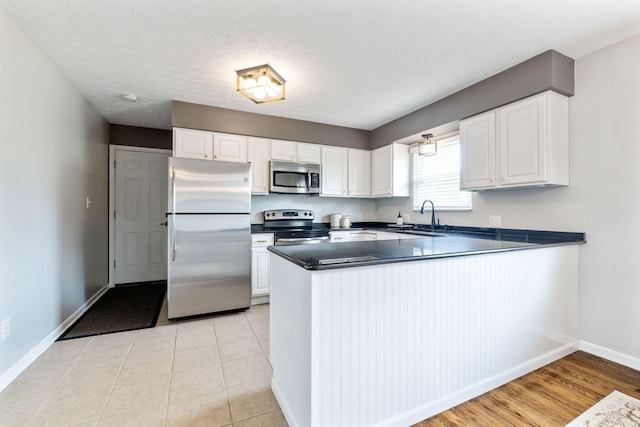 kitchen with white cabinets, kitchen peninsula, sink, and appliances with stainless steel finishes