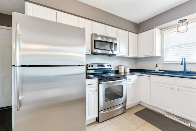 kitchen featuring stainless steel appliances, white cabinetry, and sink