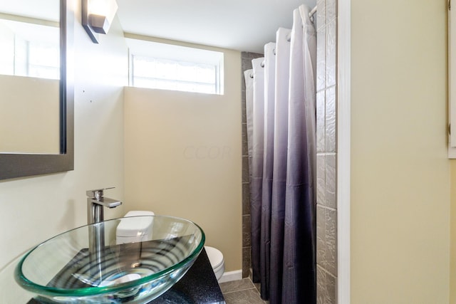 bathroom featuring toilet, curtained shower, and sink