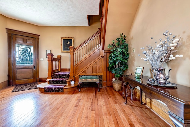 foyer with light wood-type flooring and a textured ceiling