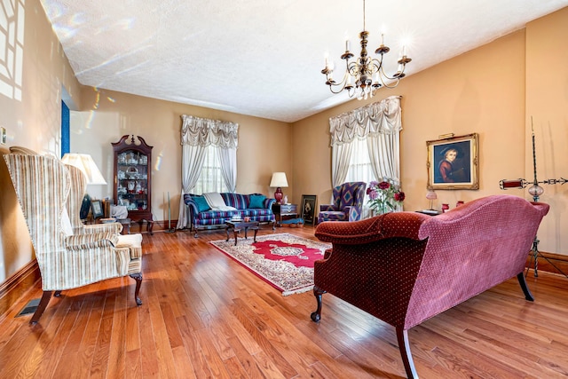 living room with a chandelier, a wealth of natural light, wood-type flooring, and a textured ceiling