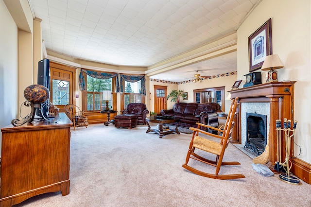 living room with ceiling fan, light colored carpet, ornamental molding, and a tile fireplace