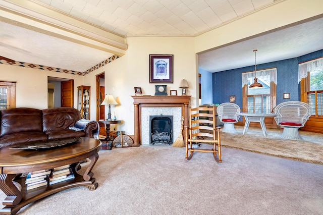 carpeted living room with beamed ceiling, a stone fireplace, and ornamental molding