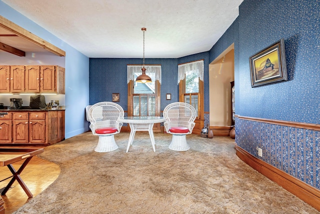 dining room featuring light carpet, beamed ceiling, and a textured ceiling