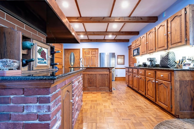 kitchen featuring light parquet floors, sink, dark stone countertops, black microwave, and stainless steel refrigerator