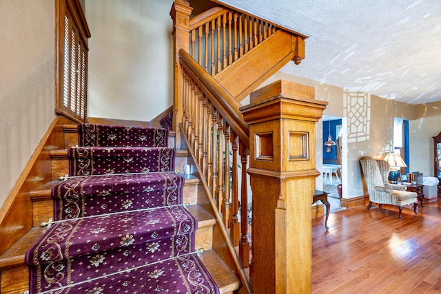 stairs featuring hardwood / wood-style flooring and a textured ceiling