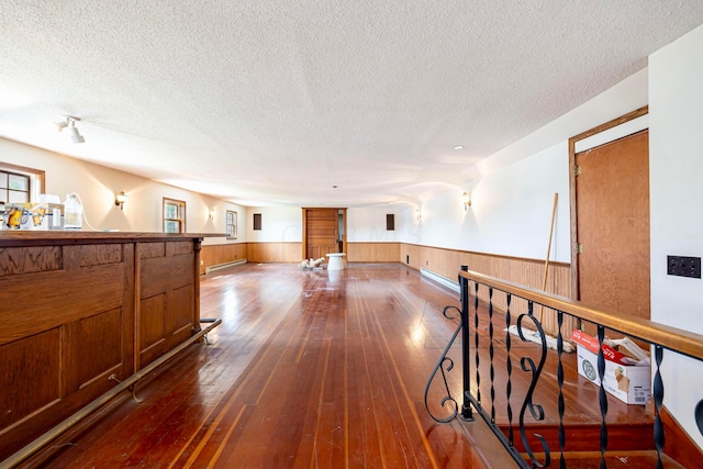 hall with a textured ceiling, dark hardwood / wood-style floors, and baseboard heating