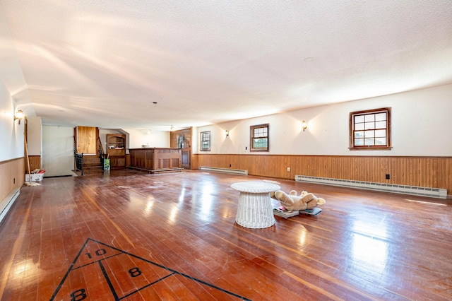 interior space with a textured ceiling, hardwood / wood-style flooring, and a baseboard heating unit