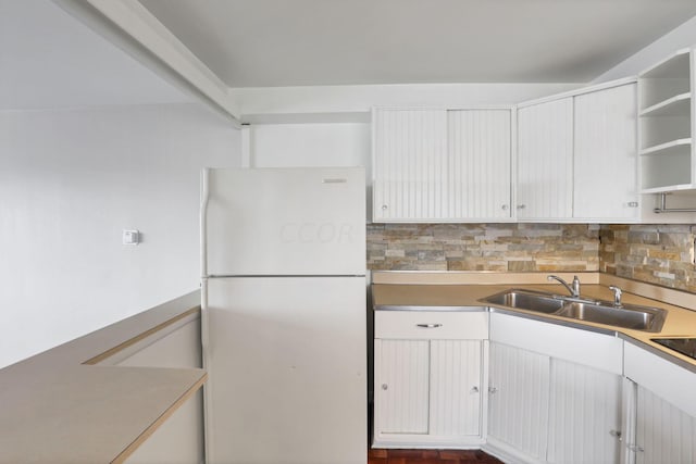 kitchen with tasteful backsplash, white cabinetry, sink, and white fridge